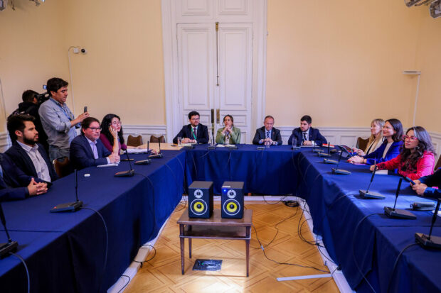 Autoridades de la Segpres y representantes del Partido Comunista sentados en una mesa en forma de U durante una reunión de trabajo en un salón oficial.