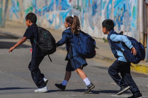 Tres niños escolares corriendo.
