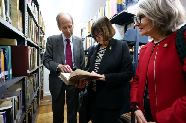 Tres personas viendo un libro al mismo tiempo.