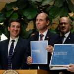 Autoridades del gobierno de Chile presentan el documento oficial del "Plan Operativo de Seguridad Pública" impreso en carpetas azules, durante un punto de prensa institucional.
