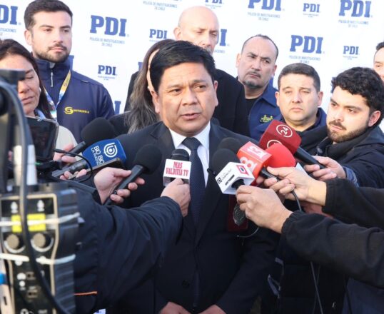 El jefe de la Región Policial de la PDI de Los Ríos y prefecto inspector, José Miguel Cea, en un punto de prensa rodeado por micrófonos de distintos medios de comunicación.