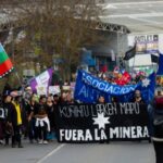 Comunidades anuncian ofensiva legal y movilización tras aprobación de minera de tierras raras Multitud de personas camina en en una manifestación entre lienzos y banderas.